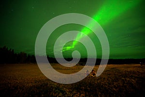 Two men on a chair watching Aurora borealis or Northern lights in Yellowknife, Canada, on August,