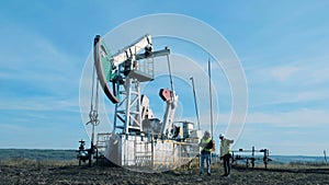 Two men check a working oil tower. Fossil Fuel, Oil industry concept.