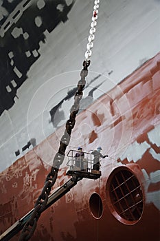 Two men in cherry picker working at ship in dry dock low angle view photo