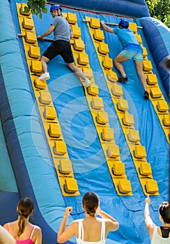 Two men climbing on inflatable castle with wooden sticks