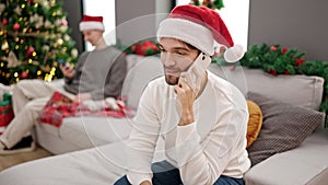 Two men couple celebrating christmas talking on smartphone at home