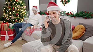 Two men couple celebrating christmas talking on smartphone at home