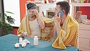 Two men couple having medical phone consultation at dinning room