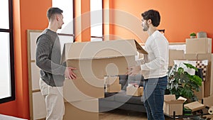 Two men couple holding carboard box at new home