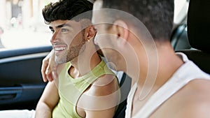 Two men couple hugging each other sitting on taxi speaking at street