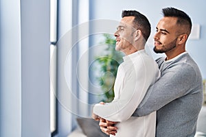 Two men couple hugging each other standing at home