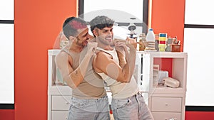 Two men couple singing song using kitchen utensil as a microphone at dinning room