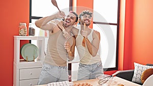 Two men couple singing song using kitchen utensil as a microphone at dinning room