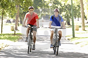 Two Men Cycling Through Park