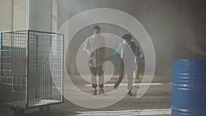 Two men dancing in the dark and dusty room of abandoned building. Teenagers making dance move simultaneously, holding