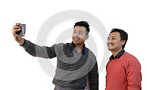 Two men with different ethnicity taking selfie photograph in a mobile phone isolated in white background with space for