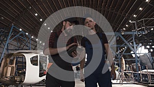 Two men discussing in aircraft hangar