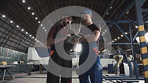 Two men discussing in aircraft hangar