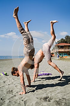 Two men doing handstand for strength and balance on beach