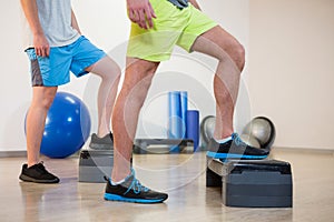 Two men doing step aerobic exercise on stepper