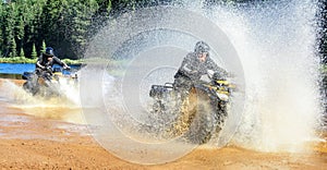 Two Men driving motocross ATV quad through splashing river lake water with high speed. Foy, Foyross Lake, Sudbury