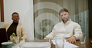 Two men engage in a conversation during a business meeting in a modern office setting, depicting teamwork and