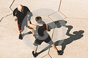 Two men exercising and fighting in outside. Boxer in gloves is training with a coach