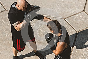 Two men exercising and fighting in outside. Boxer in gloves is training with a coach