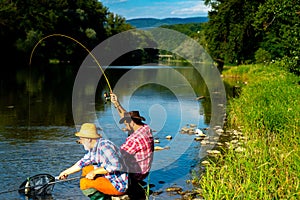 Two men fishing on river. Man catching fish. Fly fishing adventures. Mature man fly fishing. Fishman crocheted spin into