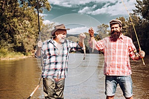 Two men friends fisherman fishing on river. Old father and son with rod fishing at riverside. Recreational activity