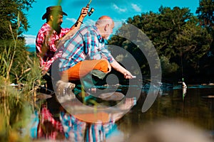 Two men friends fisherman fishing on river. Old father and son with rod fishing at riverside. Recreational activity.