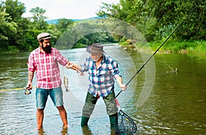 Two men friends fisherman fishing on river. Old father and son with rod fishing at riverside. Recreational activity