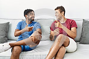 Two men friends having conversation sitting on sofa at home