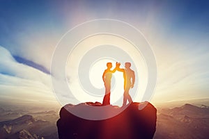 Two men, friends high five on top of the mountains. Agreement