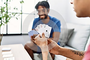 Two men friends playing poker cards sitting on sofa at home