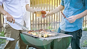 Two men are grilling on the barbecue to socialize with beer on their hands during the holidays of Covid