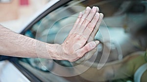 Two men with hands together on car window saying goodbye at park