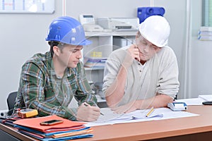 Two men in hardhats looking at blueprints