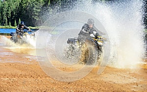 Two Men driving motocross ATV quad through splashing river lake water with high speed. Foy, Foyross Lake, Sudbury