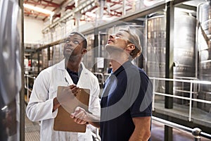 Two men inspecting vats in a modern winemaking factory