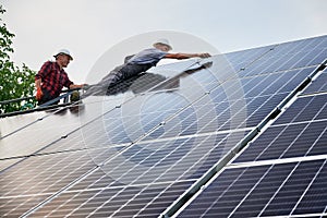 Two men installing photovoltaic solar panels outdoors.