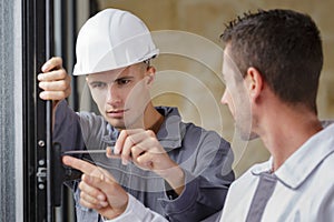 two men installing window mount at construction site