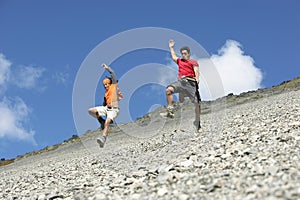 Two Men Jumping Down Scree Field