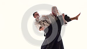 Two men in kimono practicing aikido techniques, isolated on white. Close up. Slow motion.