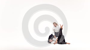 Two men in kimono practicing aikido techniques, isolated on white. Slow motion.