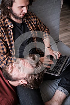 Two men with laptop on the sofa at home