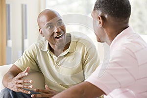 Two men in living room talking and smiling