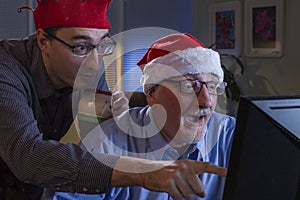 Two men look surprised while looking at computer during holiday season, horizontal