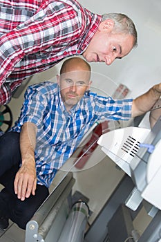 two men looking at printing machine