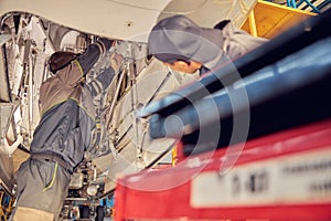 Two men mechanics examine an open jet part in an aircraft hangar