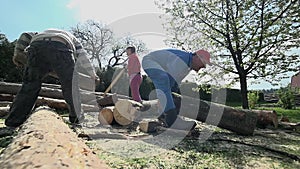 Two men moving big logs in slow motion