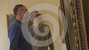 Two men in a Museum, looking at exhibits, and talking about art