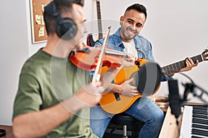 Two men musicians playing classical guitar and violin at music studio