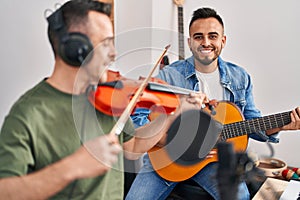 Two men musicians playing classical guitar and violin at music studio