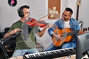 Two men musicians playing classical guitar and violin at music studio